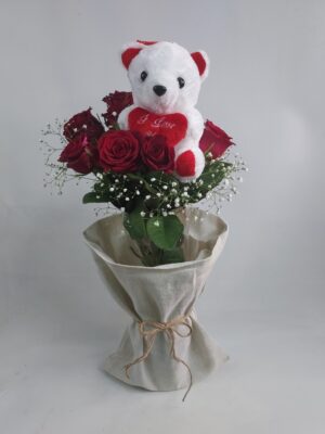 Bouquet of 10 red roses in a glass vase and a small teddy bear