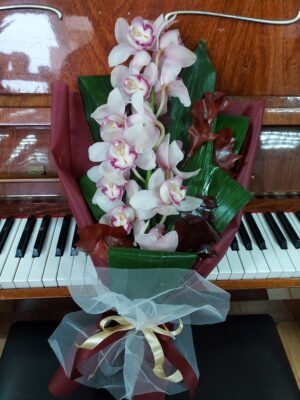 Beautiful bouquet with sprig of sympidium orchid and seasonal foliage accompaniment.