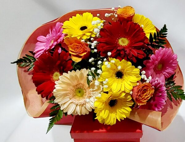Χαρούμενο χρωματιστό μπουκέτο με υπέροχες ζέρμπερες και όμορφα τριαντάφυλλα σε αποχρώσεις του κίτρινου