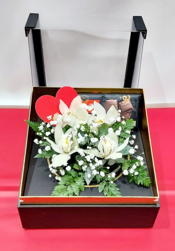 Πολυτελές  κραφτ κουτί με σκέπασμα πλέξιγλας  διάσταση 24χ24.Λουλούδια ορχιδέες συμπίντιουμ,και μαύρη σοκολάτα με γεύση πορτοκάλι